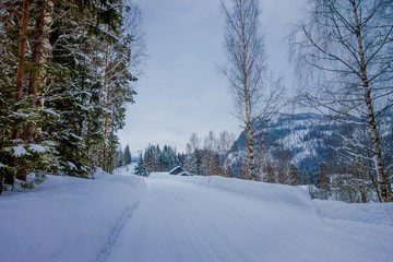 Outdoor view of winter road covered with snow and ice in the forest of Norway