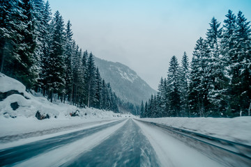 Outdoor view of winter road covered with heavy snow and ice in the forest of Norway