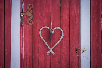 Close up of heart made of branches hanging in from a red door in a winter season in Norway