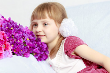 Girl sits next to a bouquet of flowers.