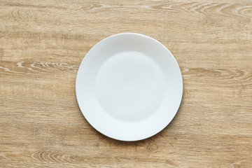 Top view of empty white food plate on a wood background. Template for your design..