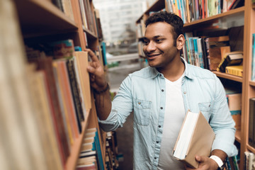Ethnic indian mixed race student in book aisle of library.