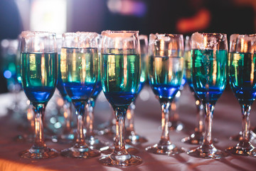 Beautiful line of different coloured cocktails on a Christmas party, tequila, martini, vodka, and others on decorated catering bouquet table