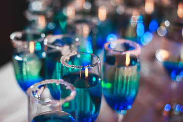 Beautiful line of different coloured cocktails on a Christmas party, tequila, martini, vodka, and others on decorated catering bouquet table