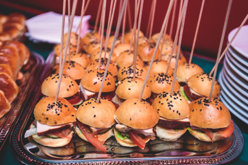 Beautifully decorated catering banquet table with different hamburgers burgers sandwiches on a plate on corporate christmas birthday party event or wedding celebration
