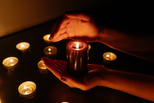 Kemerovo, Russia, fire in the mall, burning candles. Candle in female hands on black background. Many candles burning at night. Many candle flames glowing on dark background. Close-up. Free space.