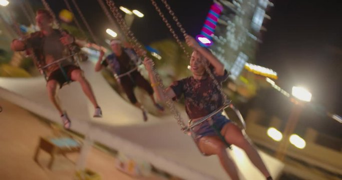Excited teenagers having fun on carousel swings at amusement park