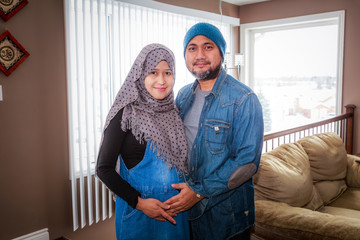 A husband with his pregnant wife inside their home during winter in Canada