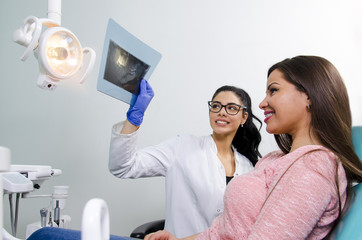 Dentist / nurse showing dental scan / x-ray to young adult female patient with braces 