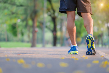 young fitness man legs walking in the park outdoor, male runner running on the road outside, asian athlete jogging and exercise on footpath in sunlight morning. Sport,healthy and wellness concepts