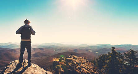 Man walking on the edge of a cliff high above the mountains