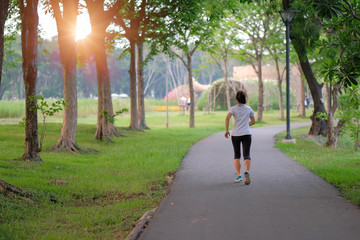 Fototapeta premium young fitness woman legs walking in the park outdoor, female runner running on the road outside, asian athlete jogging and exercise on footpath in sunlight morning. Sport,healthy and wellness concepts