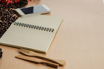 Notebook, phone on the left side of wodden table with copy space.