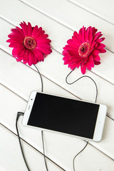headphones made frome gerbera flowers and smart phone on wooden table