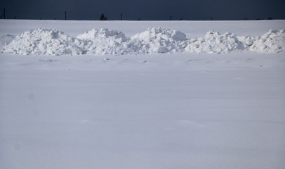 snow field. The plain is covered with white snow under a blue sky with thick white clouds. before a snowfall, a storm, a snowstorm. premonition of a blizzard. in anticipation of a blizzard.