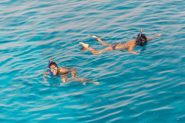 Two young women swim in the ocean with snorkeling mask. Summer background