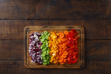 Set of sliced fresh vegetables serving on cutting board on wooden table. Top view