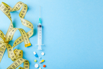 Injections for body beauty and weight loss. Tablets, syringe and yellow measuring tape.