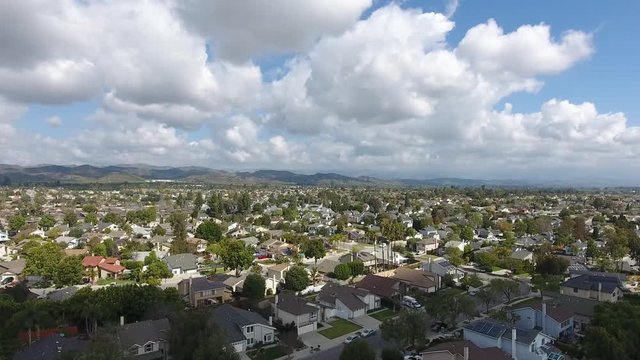 California Neighborhood Flyby Sideways - Cumulus clouds and homes give movement to a subtle parallax effect