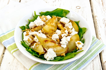 Salad from pear and spinach with feta in dish on light board