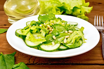 Salad from spinach and cucumber with cedar nuts on board