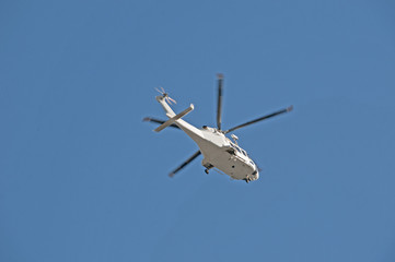 Helicopter flying overhead in a blue sky.