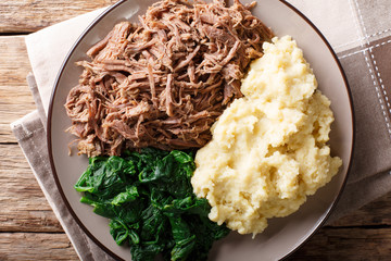 South African food: - Seswaa shredded beef with sadza porridge and spinach close-up on a plate. horizontal top view