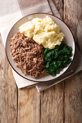 Botswana cuisine: seswaa beef stew with pap porridge and spinach close-up on a plate. Vertical top view
