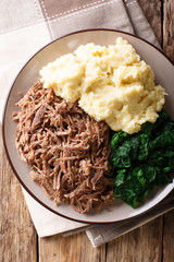 Botswana food - Seswaa stewed beef with Sadza from corn flour and spinach, close-up. Vertical top view