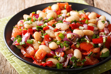 Fresh Piyaz salad with beans, tomatoes, onions, peppers and cilantro close-up on a plate. horizontal