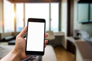 A man hand holding smart phone device in the bright office room interior.
