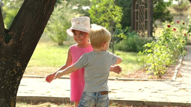 A little boy hugs a girl in the Park in the summer at sunset. Cute little kids hugging in Sunny summer Park.