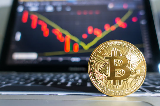 Golden Bitcoin laptop keyboard with stock exchange graph background. Digital money concept.