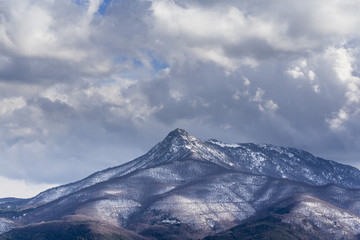 Naklejka na ściany i meble Snowy peak mountain on a deep cloudscape landscape