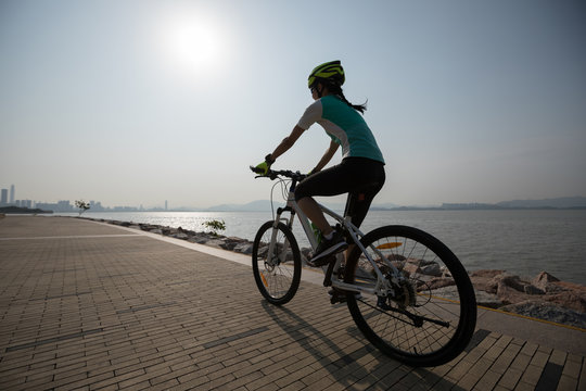 sportswoman cyclist riding mountain bike on seaside