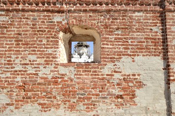 Окно в кирпичной стене сквозь которое видно церковь