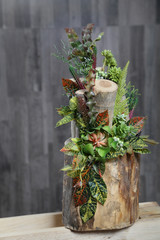 Floral arrangement of multicolored flowers, leaves and berries in wooden stump.