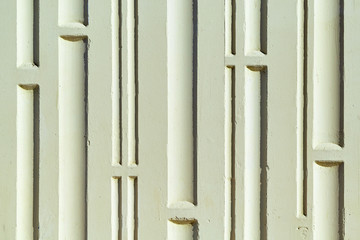 Wall of the building with a relief surface. A pattern of vertical grooves and horizontal partitions. The wall is painted with green paint. A wall of concrete. The deepening of wide and narrow.