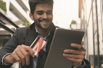 Businessman holding credit card and digital tablet.