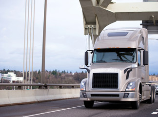 Modern big rig semi truck tractor running on the bridge on the interstate highway