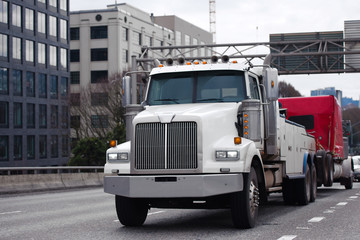 Towing powerful semi truck tow broken big rig semi truck fleet on the city street traffic