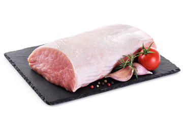 Raw sliced pork loin with tomato, pepper, rosemary and garlic on the background of a slate board....