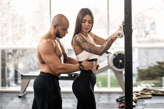 Young woman with her personal trainer working out in gym