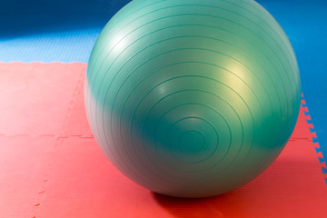 Gym green ball on red and blue soft mat