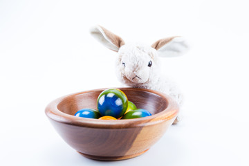 Easter bunny on a circle wood bowl holding hand painted easter eggs with white background