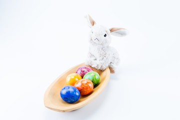 Easter bunny on a rectangular wood bowl holding hand painted easter eggs with white background