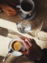 Two couple hands hold a coffee and water, date in cafe