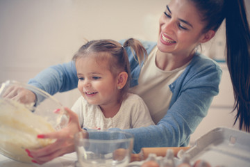 Mother and daughter baking cookie and mixing dough.