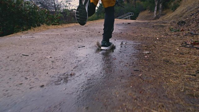 Closeup of a runner's foot splashing into a puddle. Slow Motion.