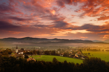 Breathtaking morning lansdcape of small bavarian village covered in fog. Scenic view of Bavarian Alps at sunrise with majestic mountains in the background.